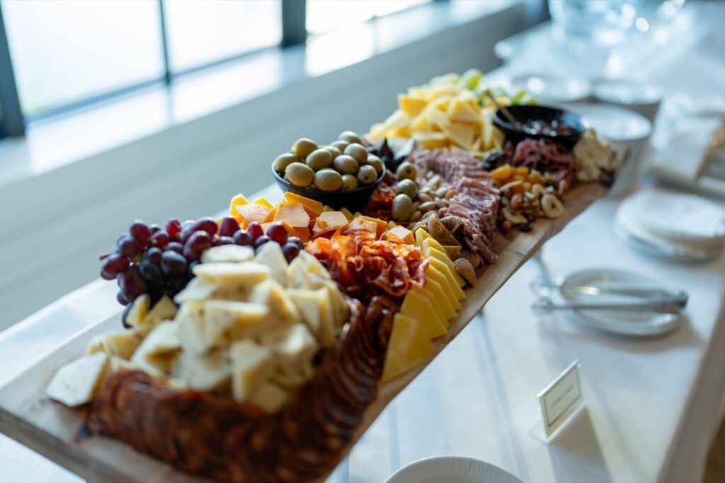 Long grazing board of cheeses, cured meats, and fruit, a food-driven option for corporate holiday parties